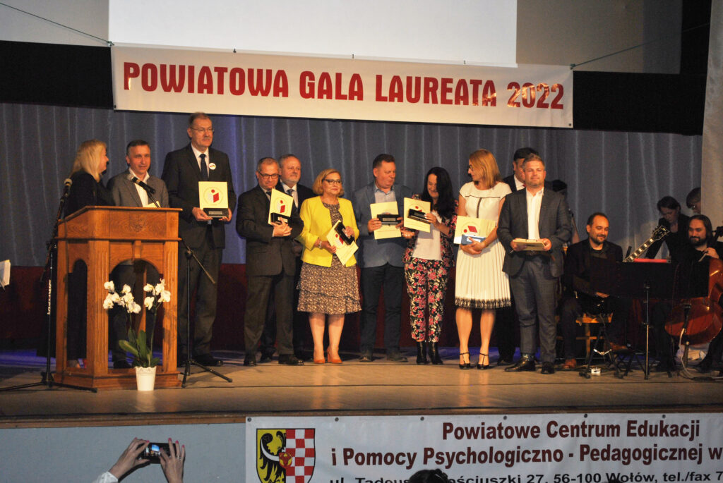 Zdjęcie grupowe Dolnośląskiego Kuratora Oświaty, przedstawicieli organów prowadzących i  dyrektor PCEiPPP w Wołowie, w tle napis POWIATOWA GALA LAUREATA 2022