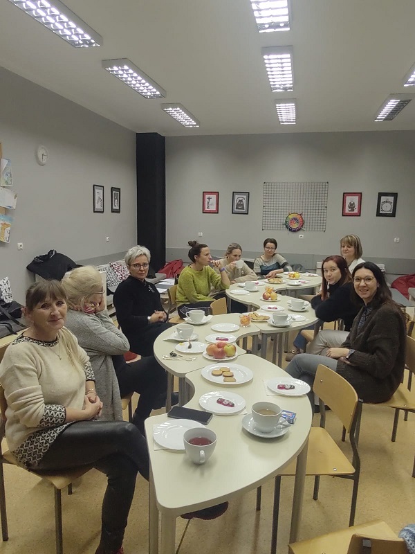 Na zdjęciu widoczna grupa nauczycielek siedzących przy stole. Dyskutują, piją kawę. 
