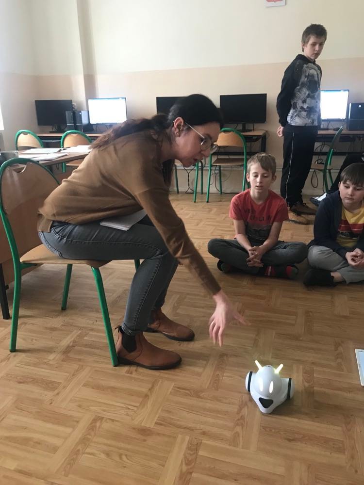 Na zdjęciu widoczna kobieta, siedzi na krześle, pokazuje coś uczniom.