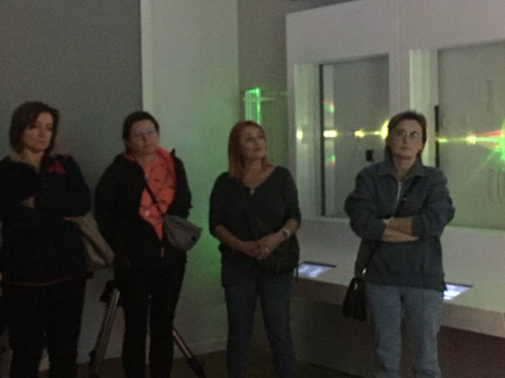 Sala, cztery uczestniczki spotkania stoją obok siebie, za nimi zielone światło