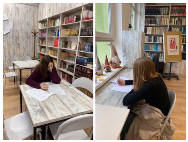 Biblioteka szkolna, w ławkach siedzą uczennice i piszą. W tle regały z książkami.