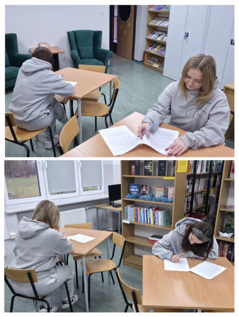 Biblioteka szkolna, w ławkach siedzą uczennice i piszą. W tle regały z książkami.