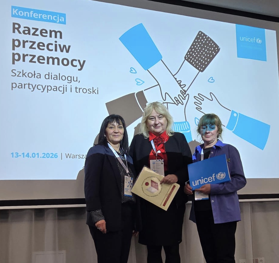 Na tle prezentacji projektu stoją trzy kobiety.                                                 