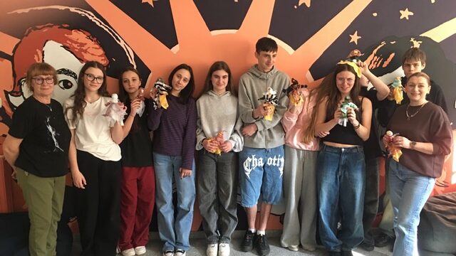 Aula szkolna, na środku kobiety, które mówią coś do uczestników