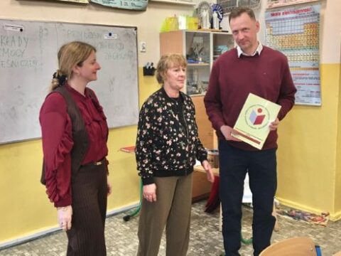 W klasie na tle białej tablicy stoją dwie kobiety i jeden mężczyzna.
