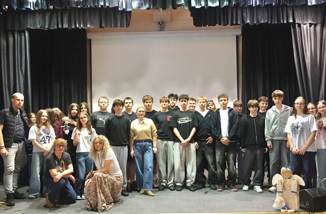 Aula szkolna, na scenie  uczestnicy zajęć.  Duża grupa uczniów i nauczyciele.