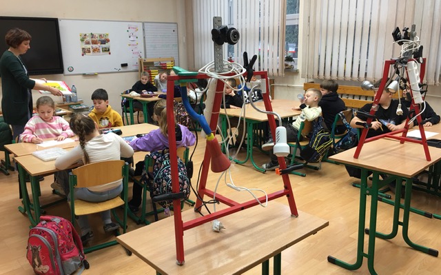 Sala lekcyjna. Dzieci przy stoliku rysują makietę i postaci do filmu. Wśród nich kobieta.
