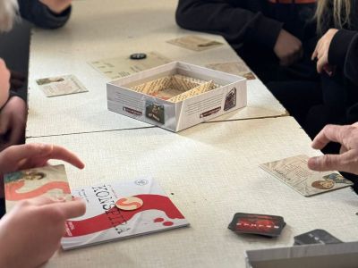 Na stole leży pudełko i karty do gry. 