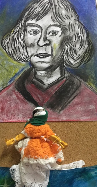 Portret  Mikołaja Kopernika,  a pod nim kolorowa lalka wykonana ze szmatek.