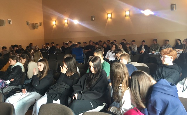 Aula szkolna, uczestnicy zajęć.  Duża grupa uczniów i nauczyciele.