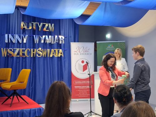 na niebieskim tle napis autyzm inny wymiar wszechświata z boku banery przednimi dwie kobiety i chłopiec