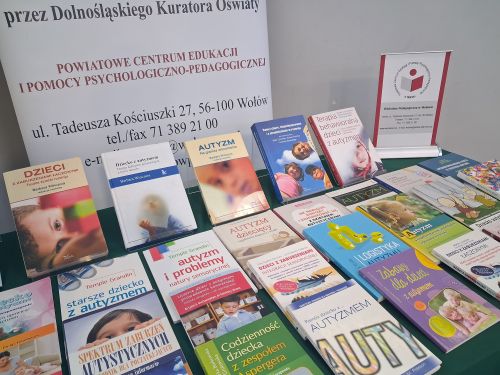 na stole leżą książki na temat autyzmu z boku stoi baner centrum 