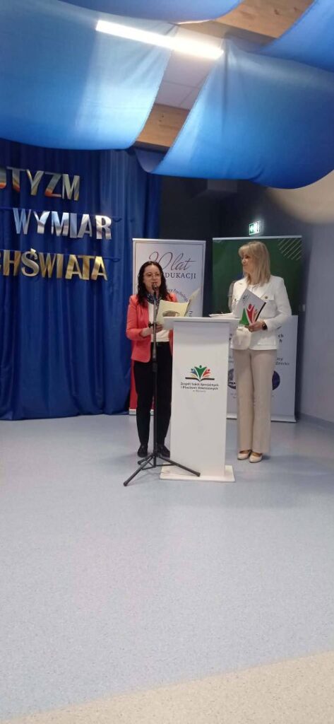 na zdjęciu dwa banery za nimi stoją dwie kobiety przy mównicy 