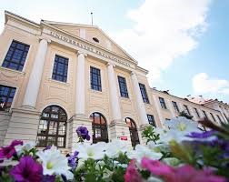 kolorowe kwiaty u dołu obrazka, w tle budynek z jasną elewacją